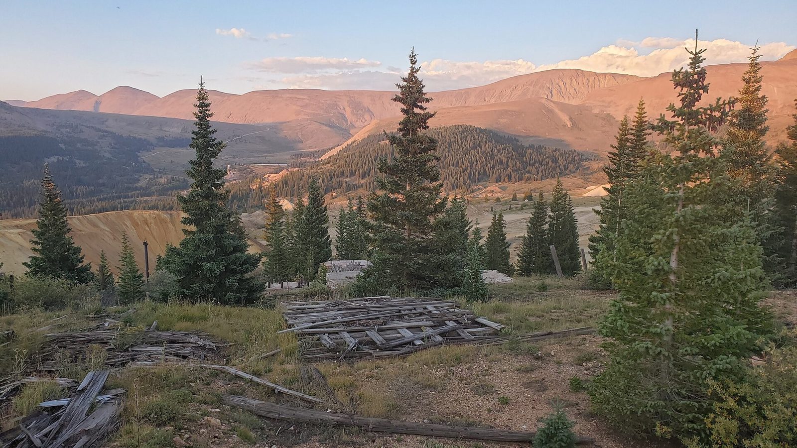 Weathered timbers of the Ibex Mine against bare orange mountains at sunset