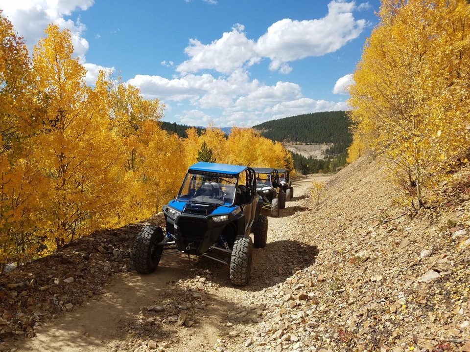 Two UTVs on a rocky mountain road lined with golden aspens